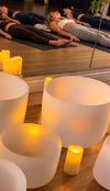 Singing bowls and candles with participants resting on yoga mats during a soundbath